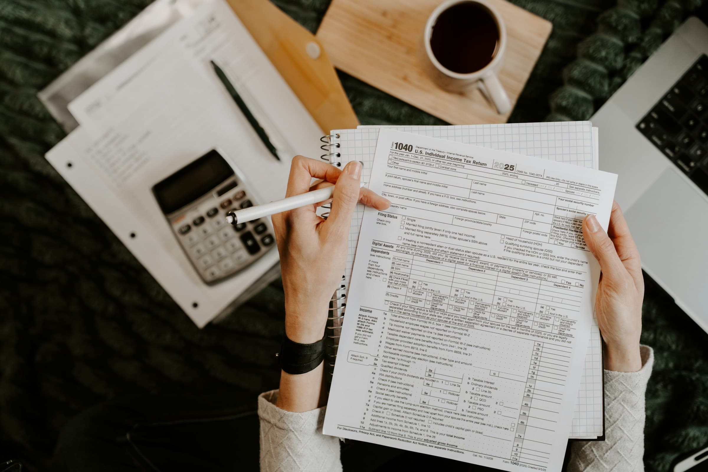 Hands with a pen reviewing financial documents beside a calculator