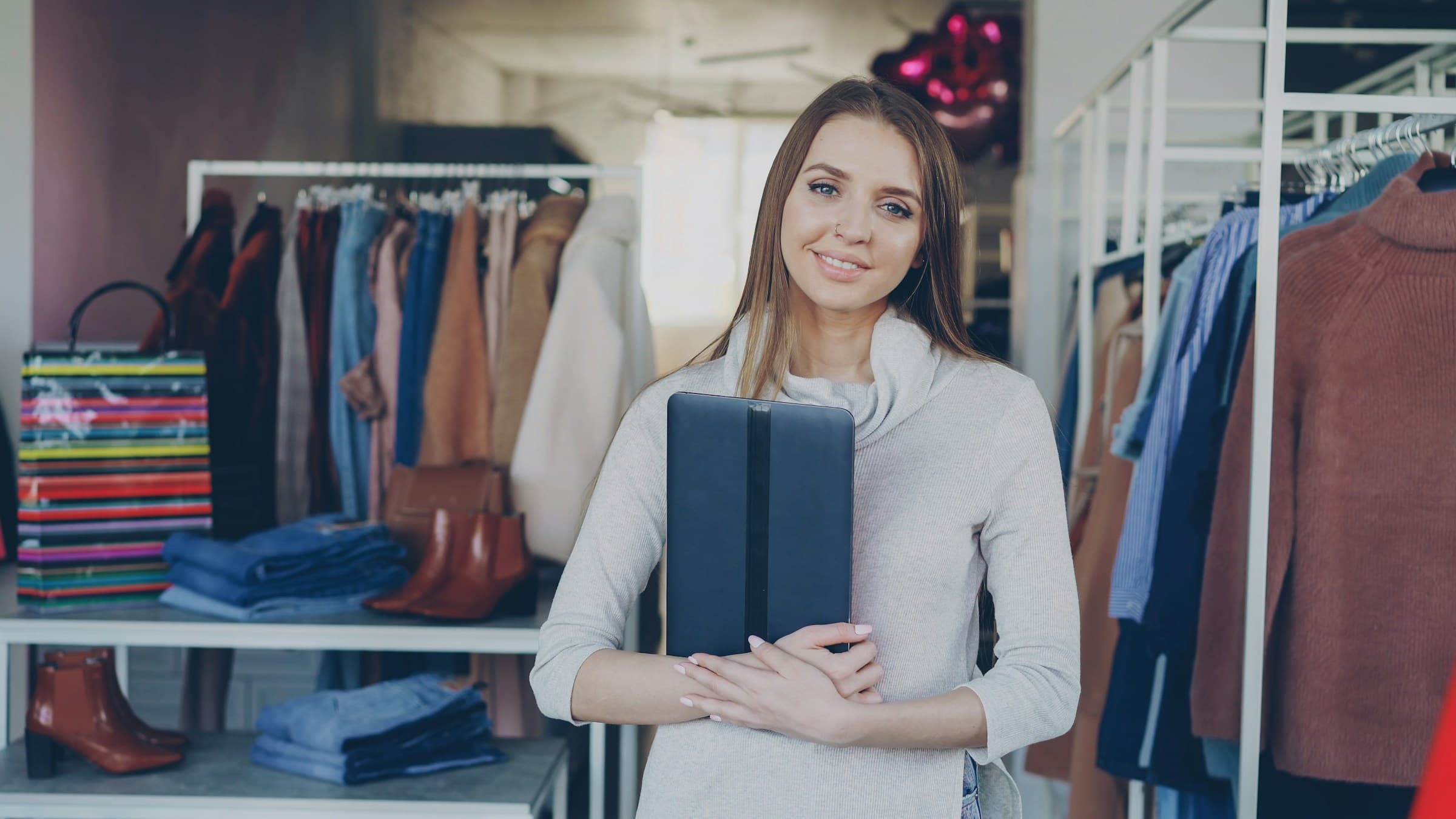 Smiling boutique owner holding a tablet in her clothing store