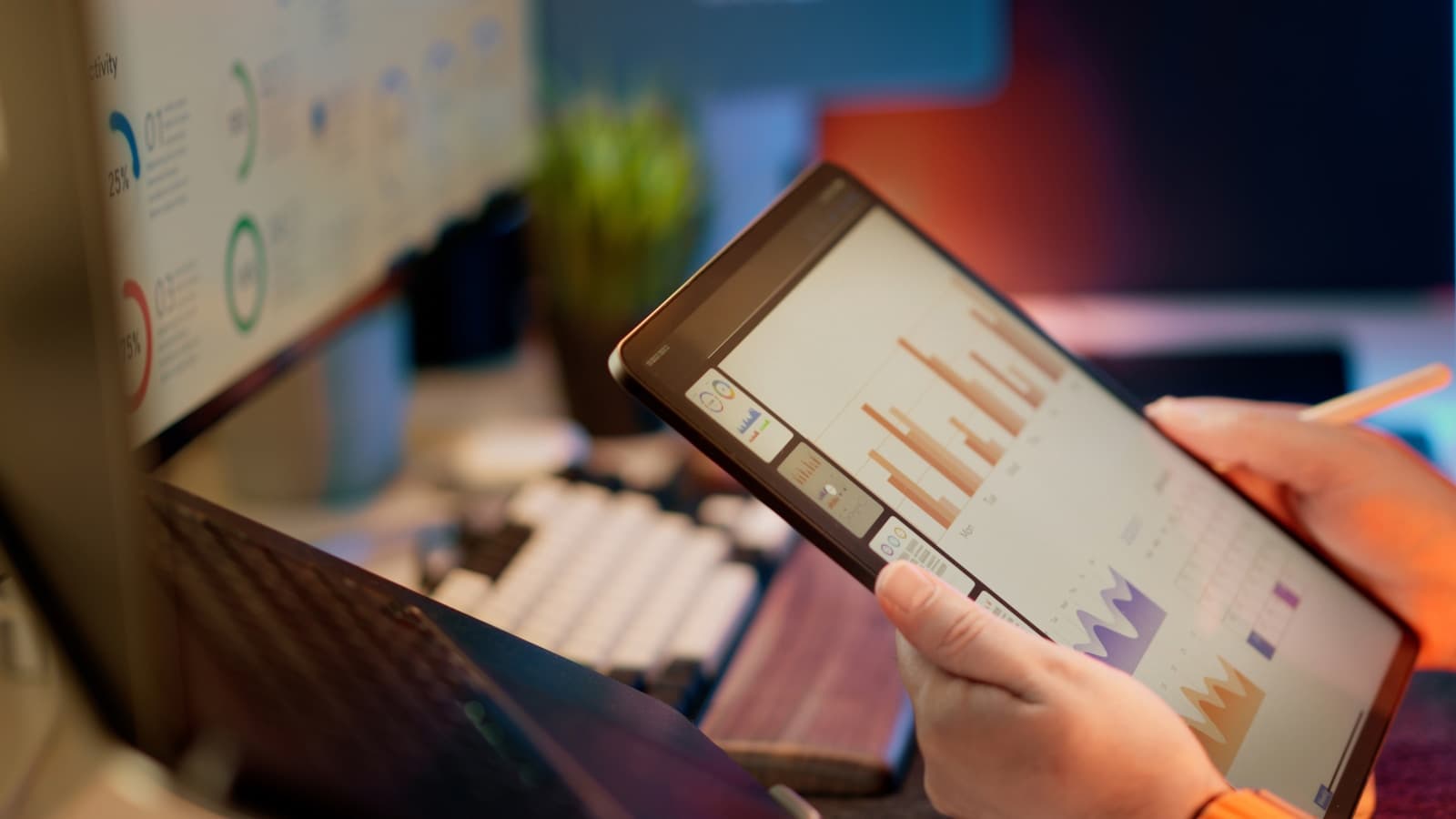 Hands holding a tablet that shows bar-chart analytics